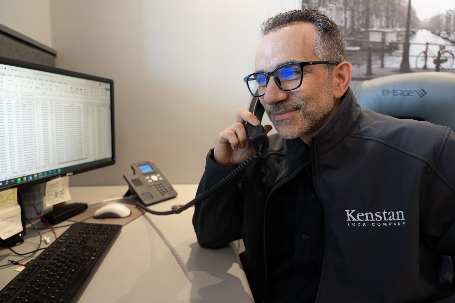 Kenstan - man on phone looking at computer monitors